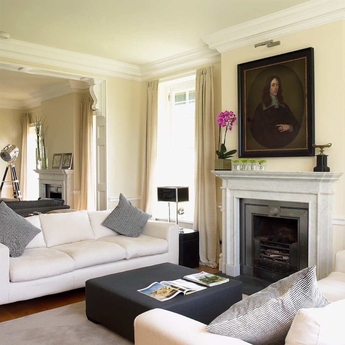 Sofa set in front of open fireplace below historical portrait of man