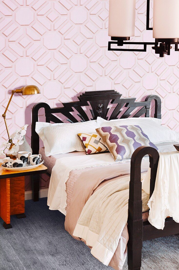 Doppelbett mit schwarzem Gestell an rosafarbener grafischer Mustertapete