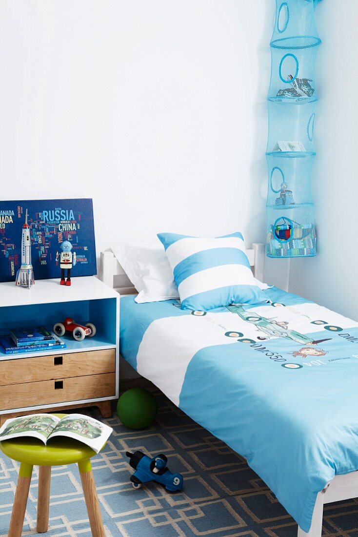 Blue teenager's bedroom with bed, bedside cabinet & storage net