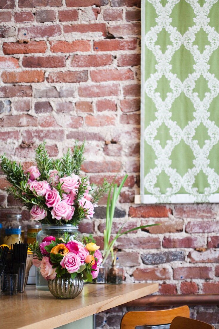 Blumendekoration vor rustikaler Backsteinwand
