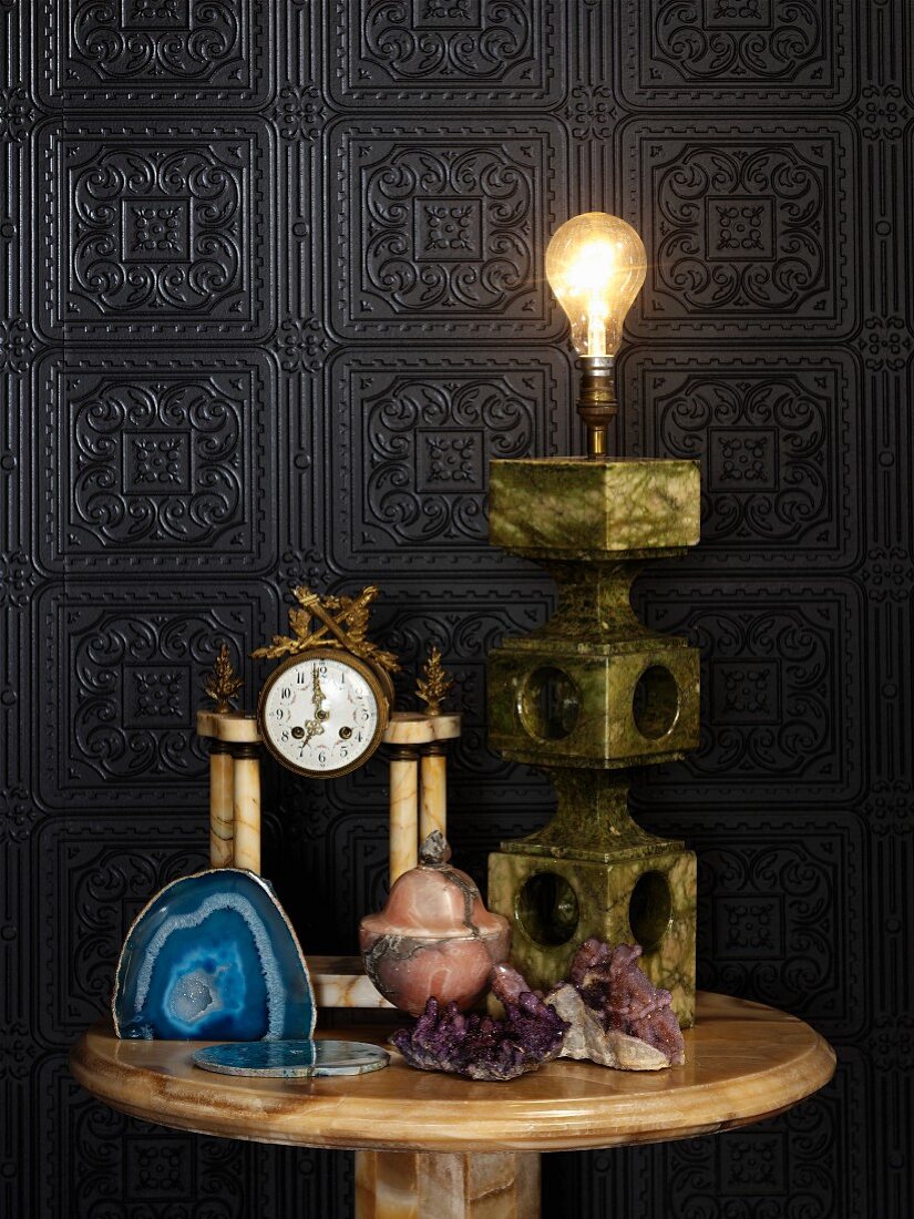 Various objects made from stone and semi-precious stone on side table against embossed wall