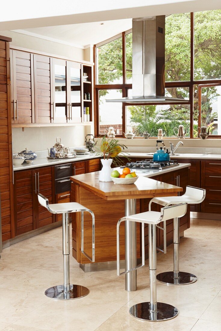 Fitted kitchen with wooden fronts and bar stools at small breakfast bar
