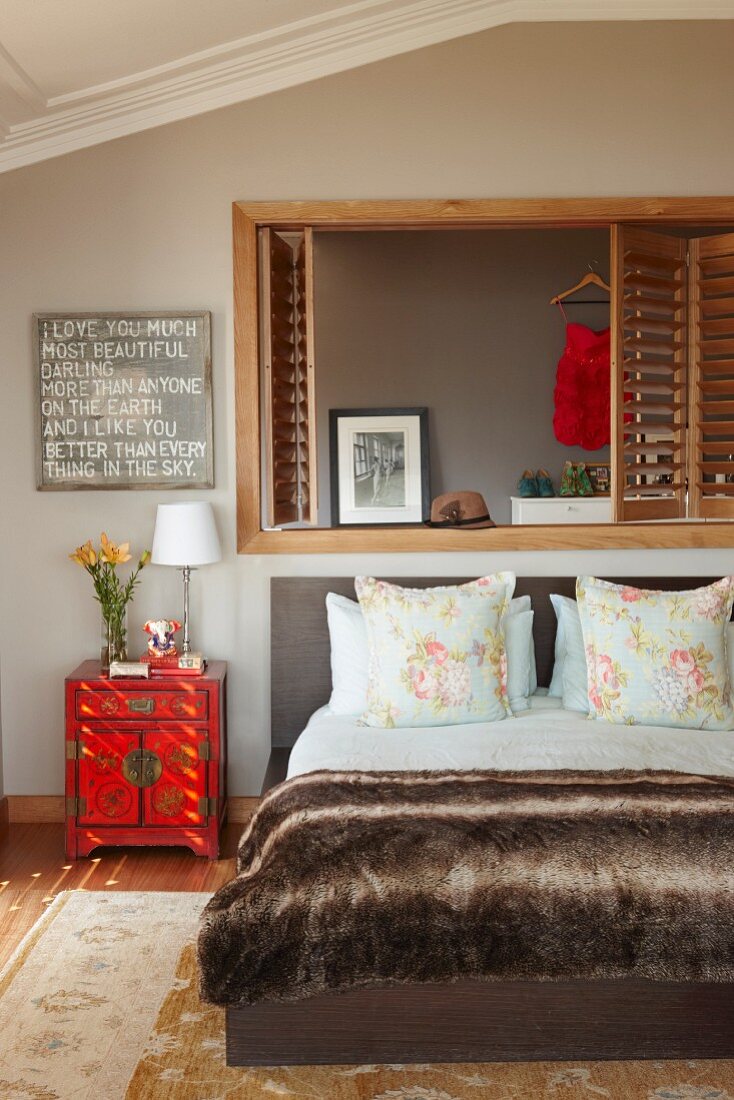 Feminin dekoriertes Schlafzimmer mit Klappläden vor stilisierter Fensternische und Liebeserklärung über Asiaschränkchen