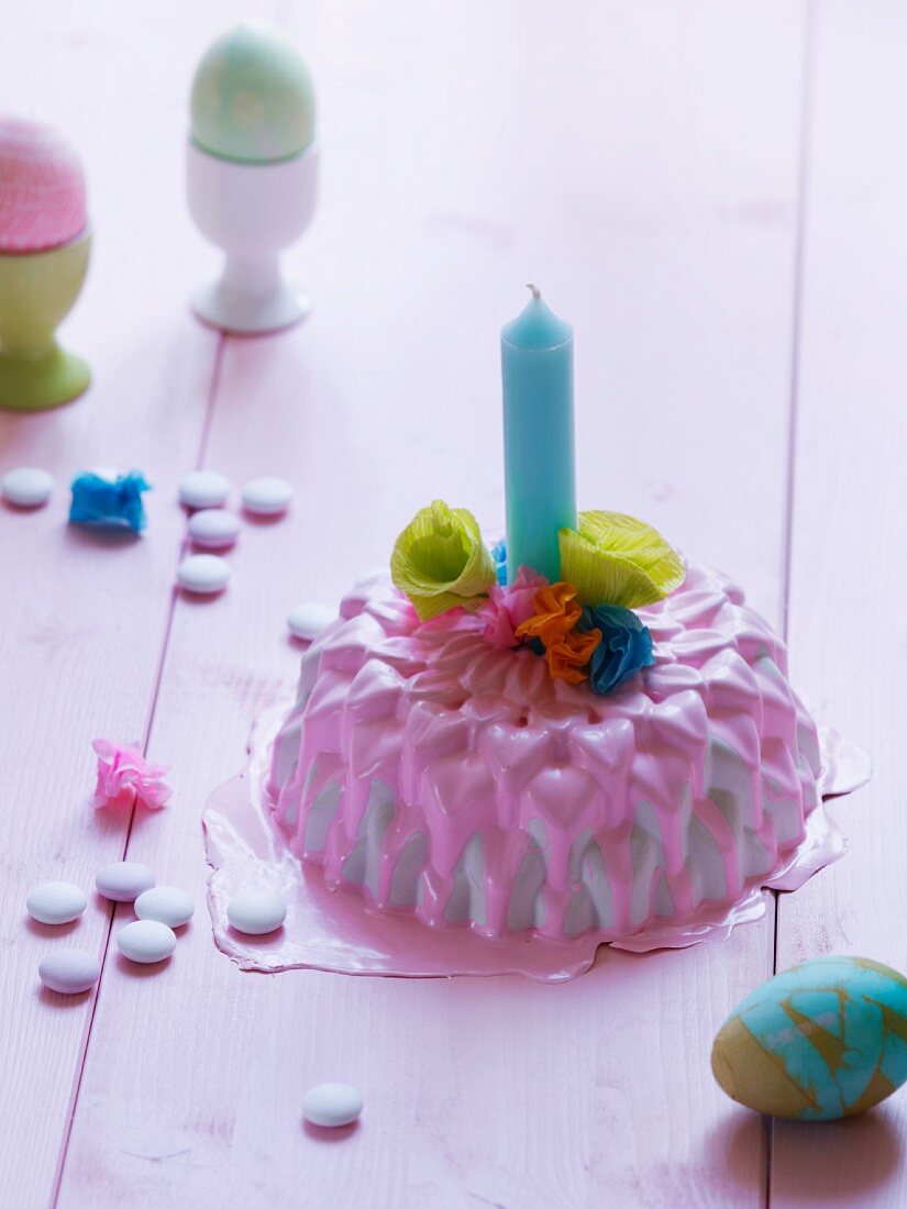 Mini-Kuchen dekoriert mit rosa Zuckerglasur, Kerze & Papierblüten