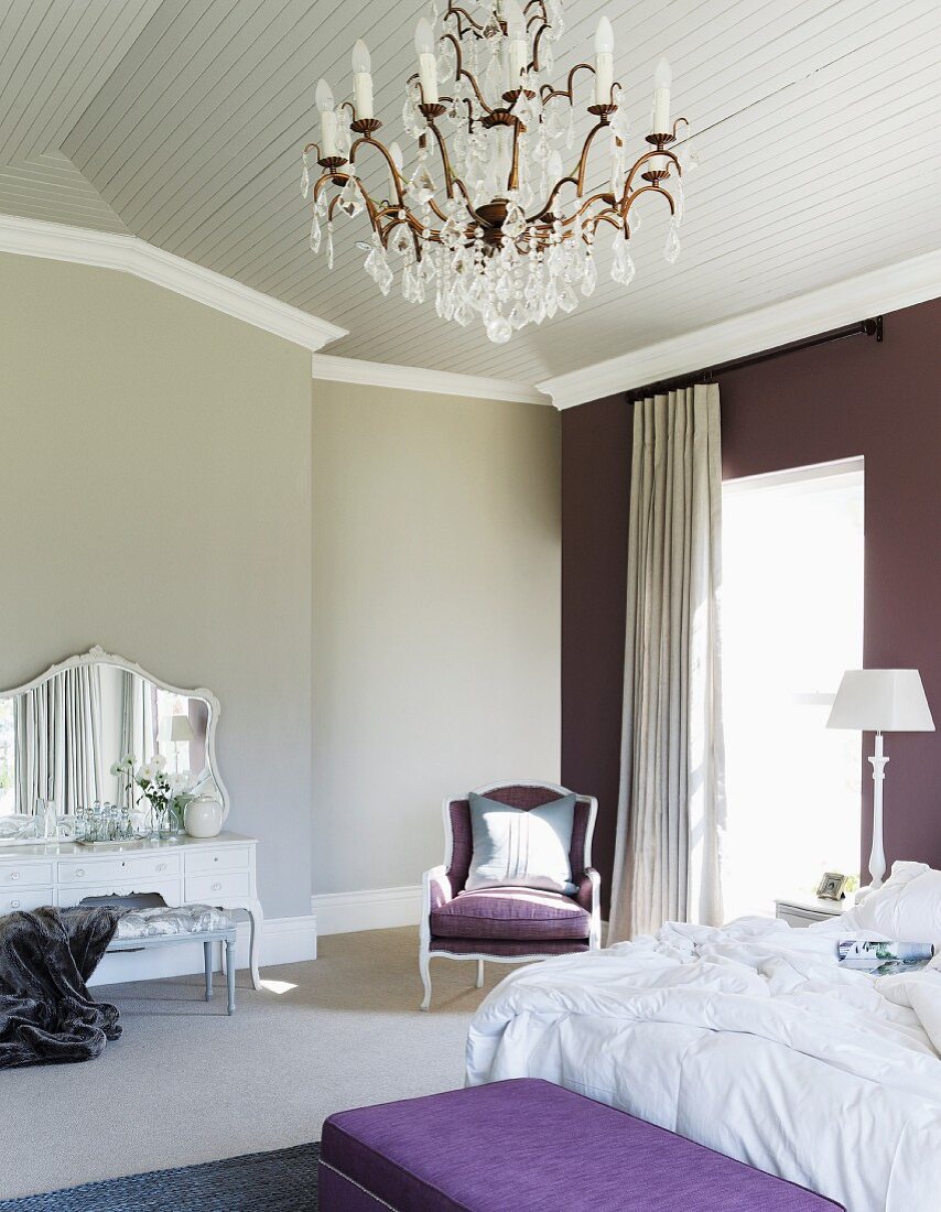Traditionell elegantes Schlafzimmer im eleganten Landhausstil mit Kristallleuchter und auberginefarbener Wand