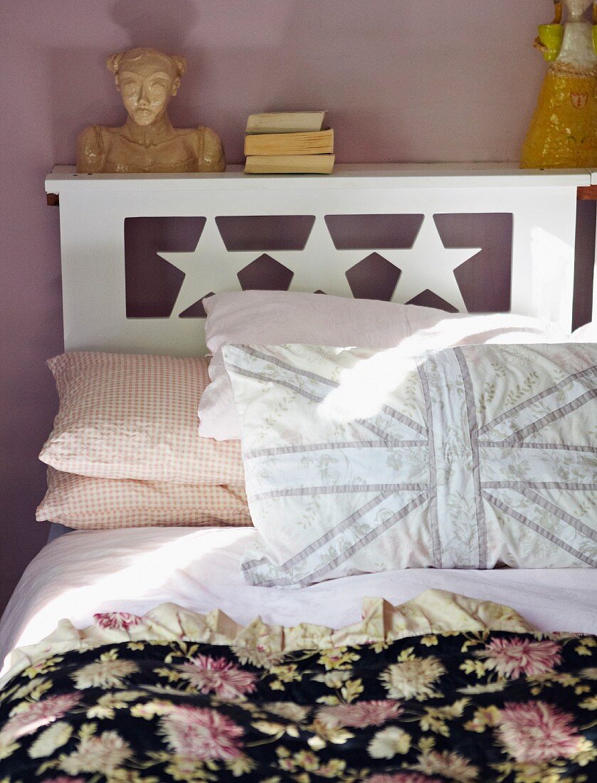 Doppelbett mit Sternenmotiv, selbstgenähten Kissen und schwarzem Bettüberwurf mit Blumenmuster
