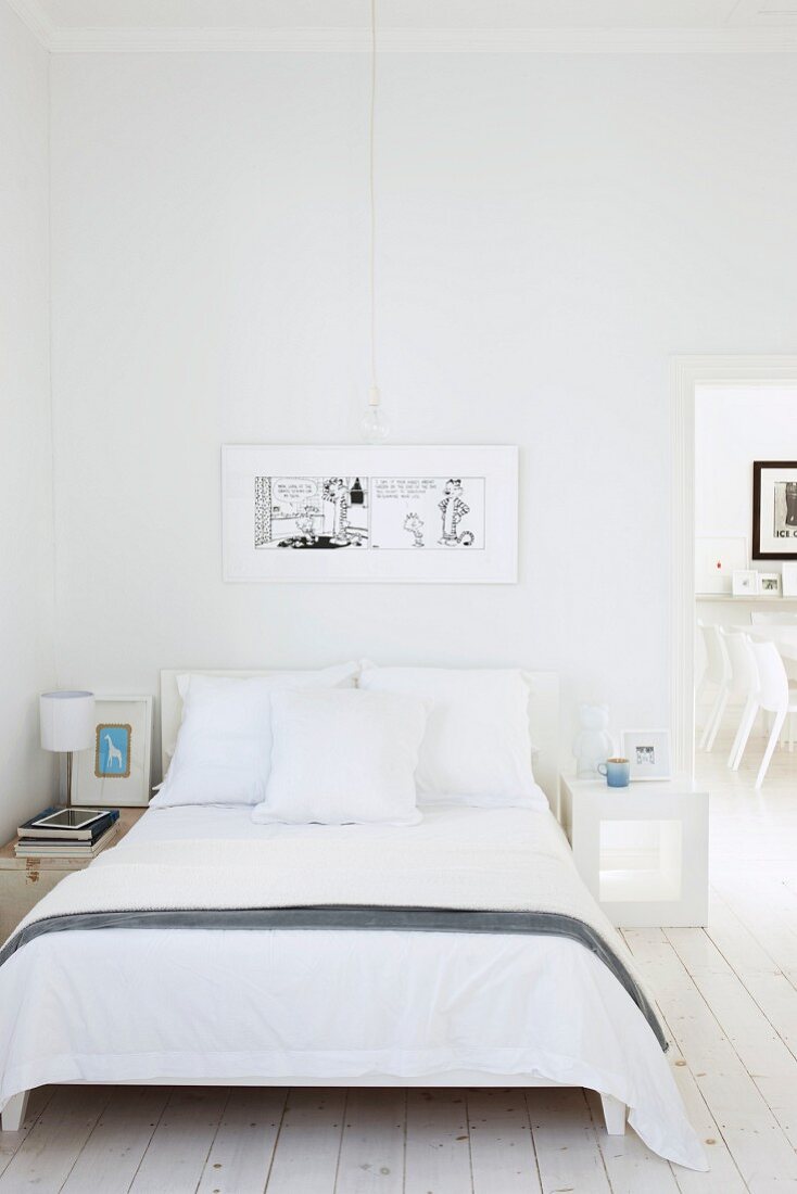 Doppelbett mit weisser Bettwäsche in minimalistischem Schlafzimmer mit offener Tür und Blick auf Stühle