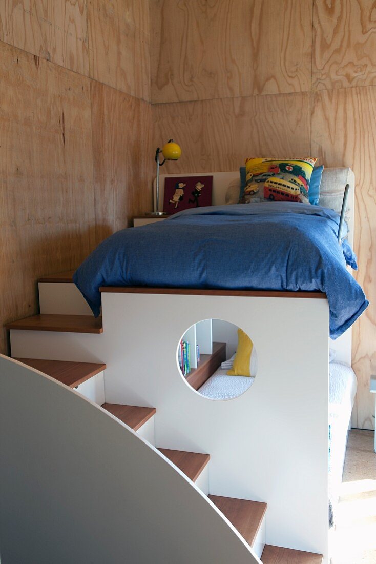 Steps leading to child's loft bed in wood-clad room