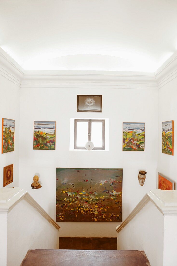 Collection of various paintings on walls of masonry staircase