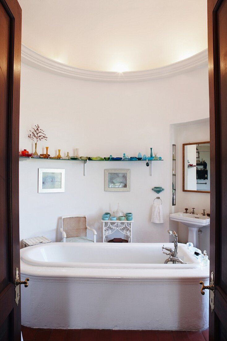 View through double doors of free-standing bathtub in centre of round bathroom