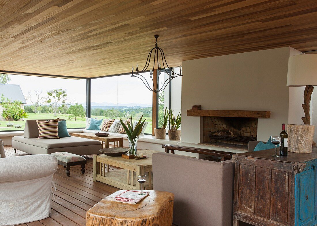 Comfortable living room with open fireplace, modern and vintage furniture and fabulous view of landscape