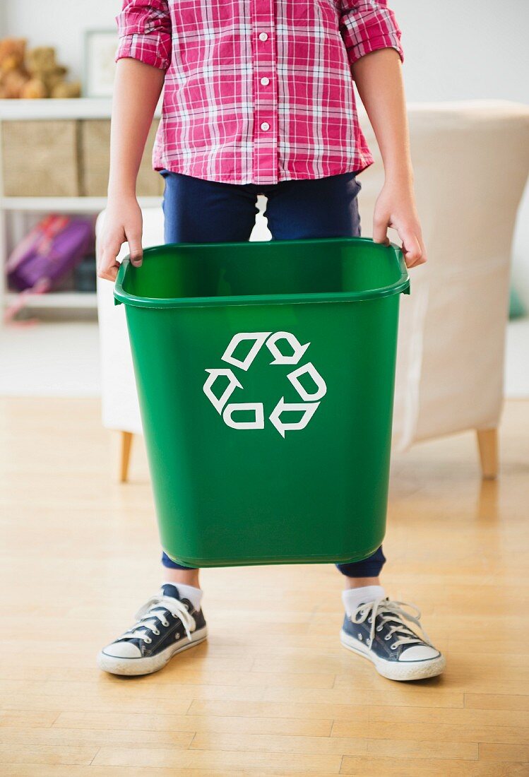 Junge trägt Abfallbehälter mit Recylingsymbol