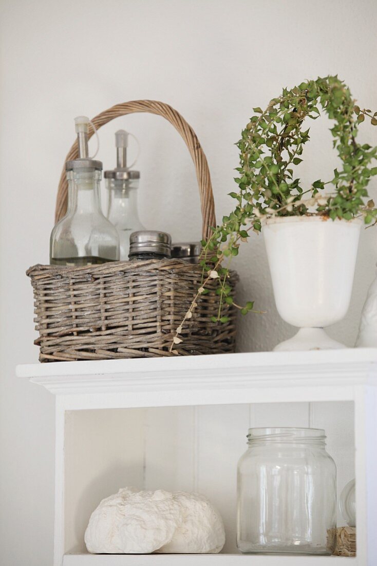 Stillleben in Landhausküche mit Korb, Zimmerpflanze und leerem Schraubglas in weißem Holzregal