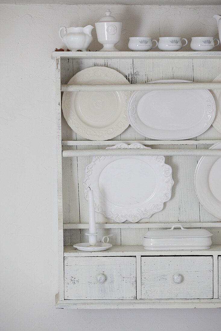 Serving platters and crockery on white-painted plate rack