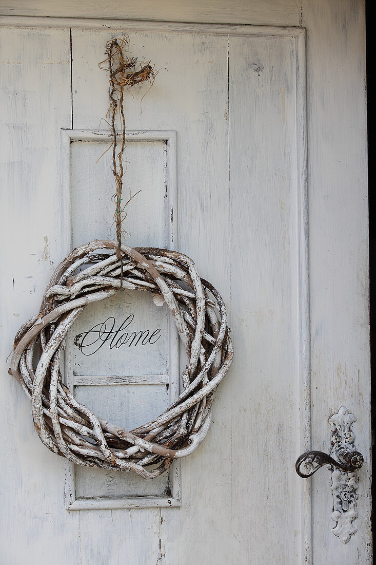 White-painted willow wreath on shabby-chic front door