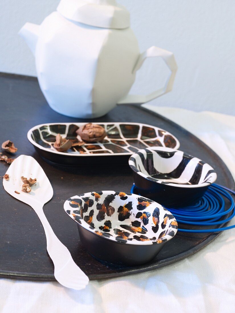 Various bowls painted with different animal-skin patterns arranged on black tray