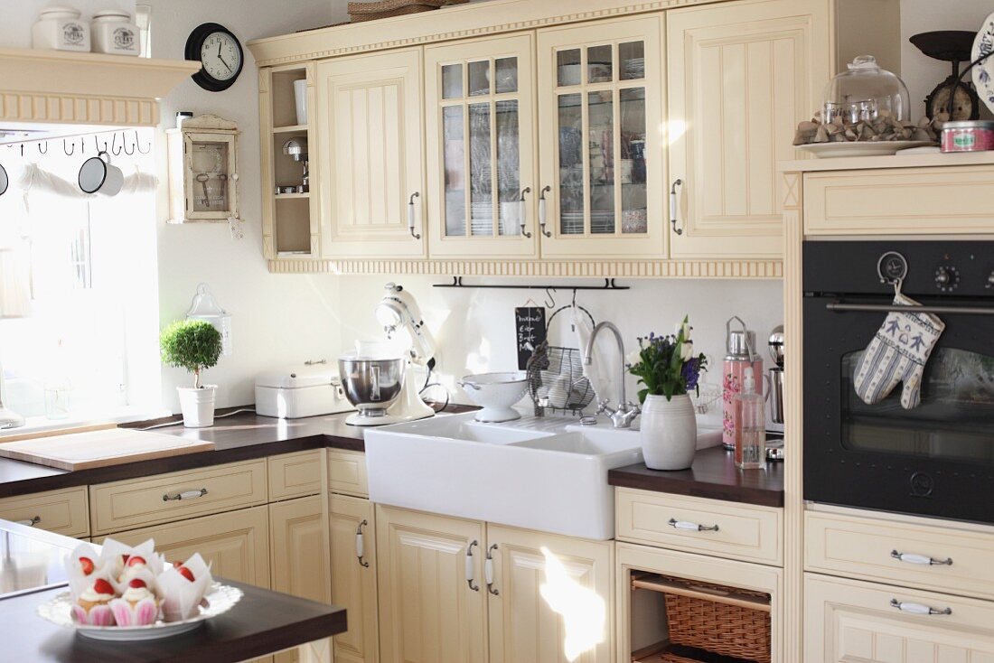Cremefarbene Einbauküche im Landhausstil mit Kassettentüren und grossem Aufsatzspülbecken aus Keramik