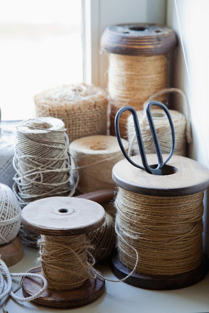Collection of twine, some on old wooden reels, in corner of windowsill