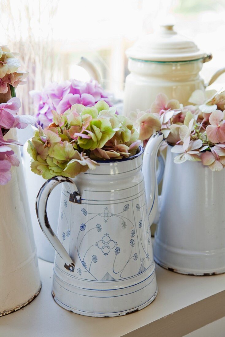 Collection of old enamel coffee pots decorated with hydrangea flowers