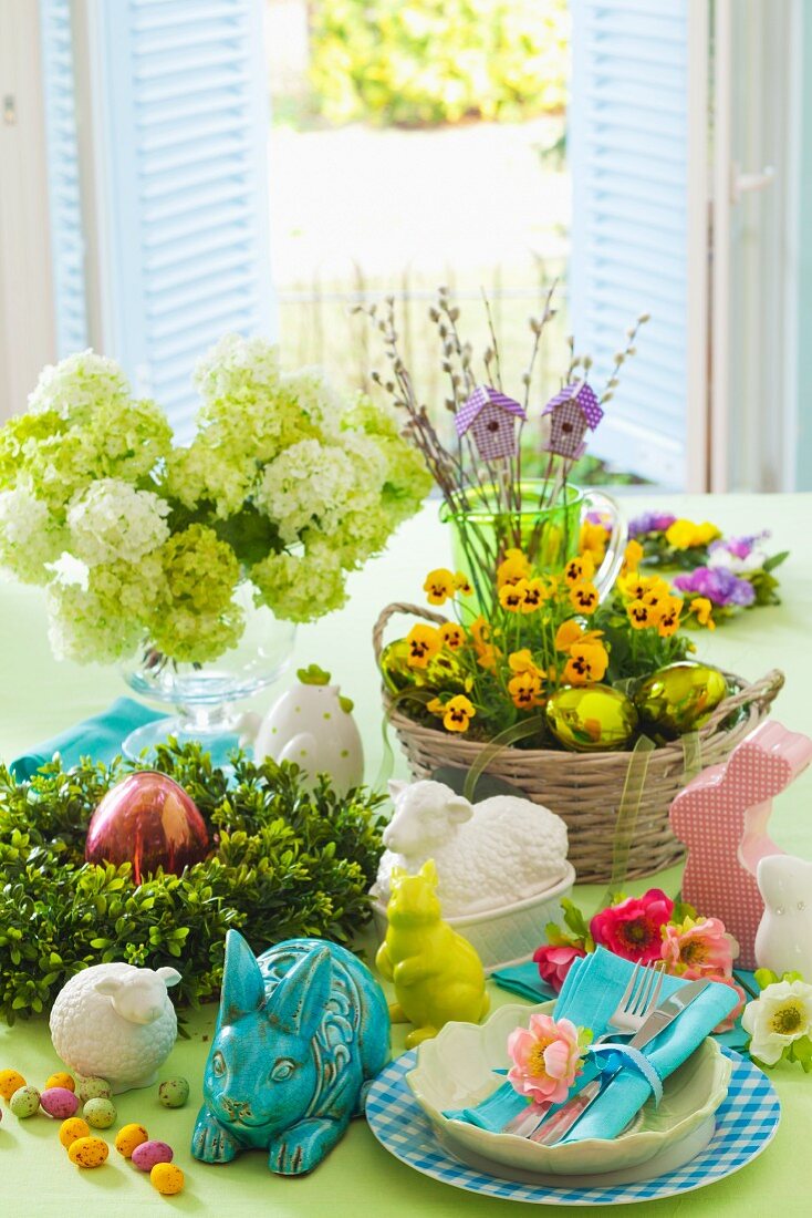 Table set for Easter with spring flowers, china rabbits and Easter place setting