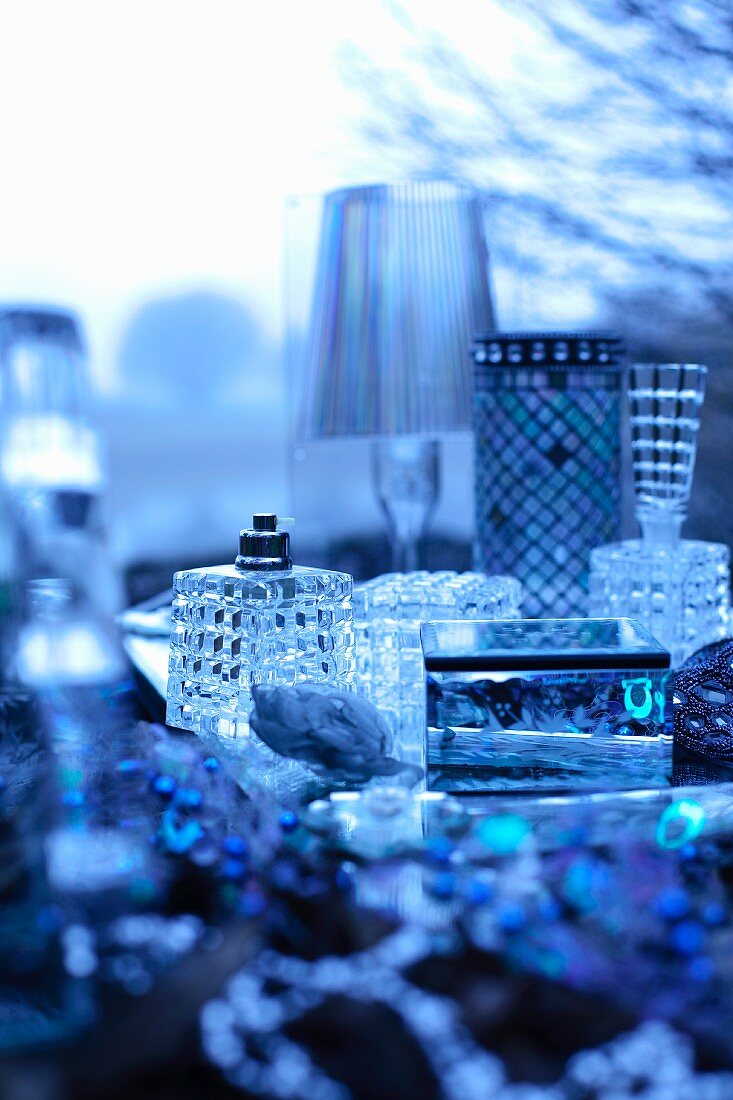 Still-life arrangement of jewellery boxes and perfume bottles in bluish light