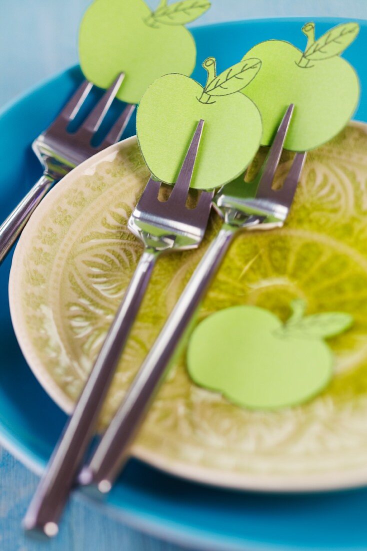 Kuchengabeln auf Teller, dekoriert mit Äpfeln aus Papier