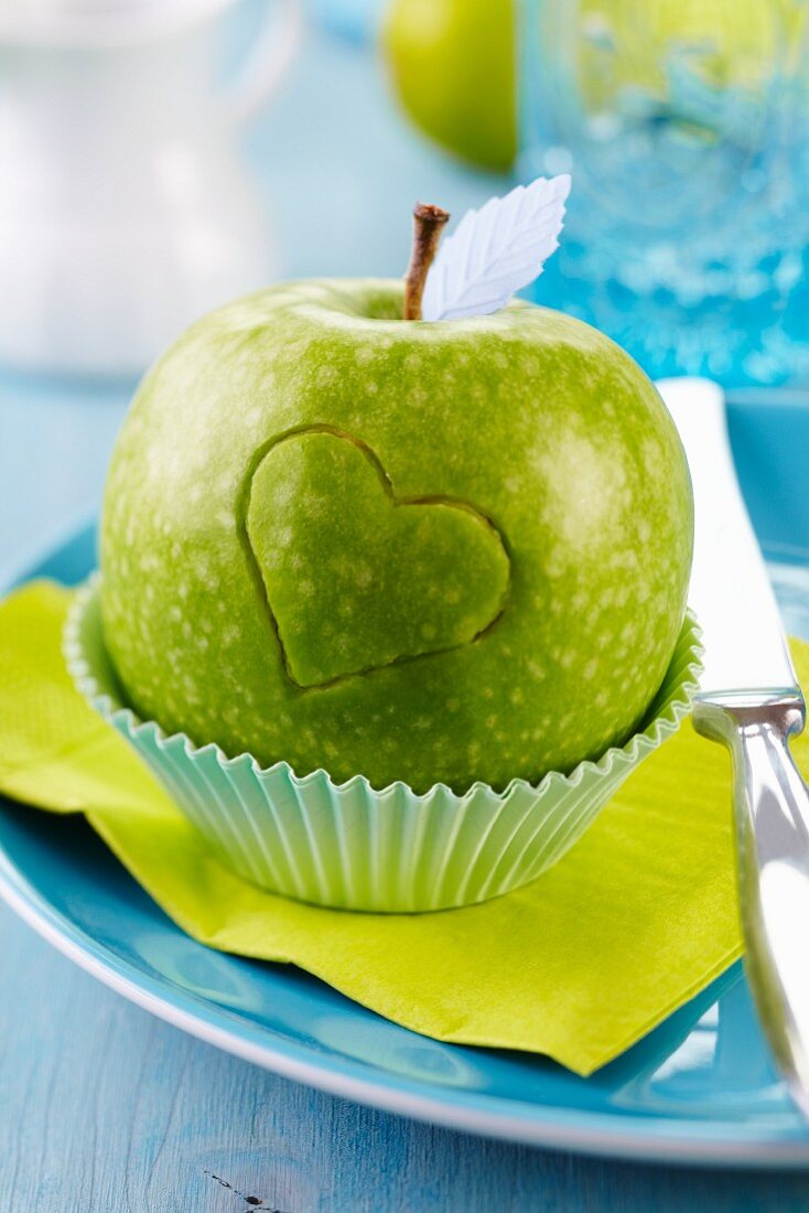 Grüner Apfel in Muffinförmchen auf Teller mit eingeritztem Herz