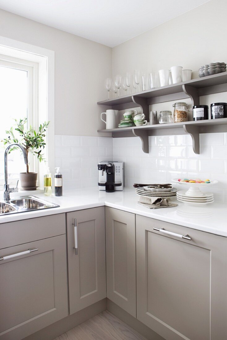 Küchenunterschränke mit modernen Kassettenfronten und offenes Regal in Grautönen, Arbeitsplatte und Wandfliesen im Weiß