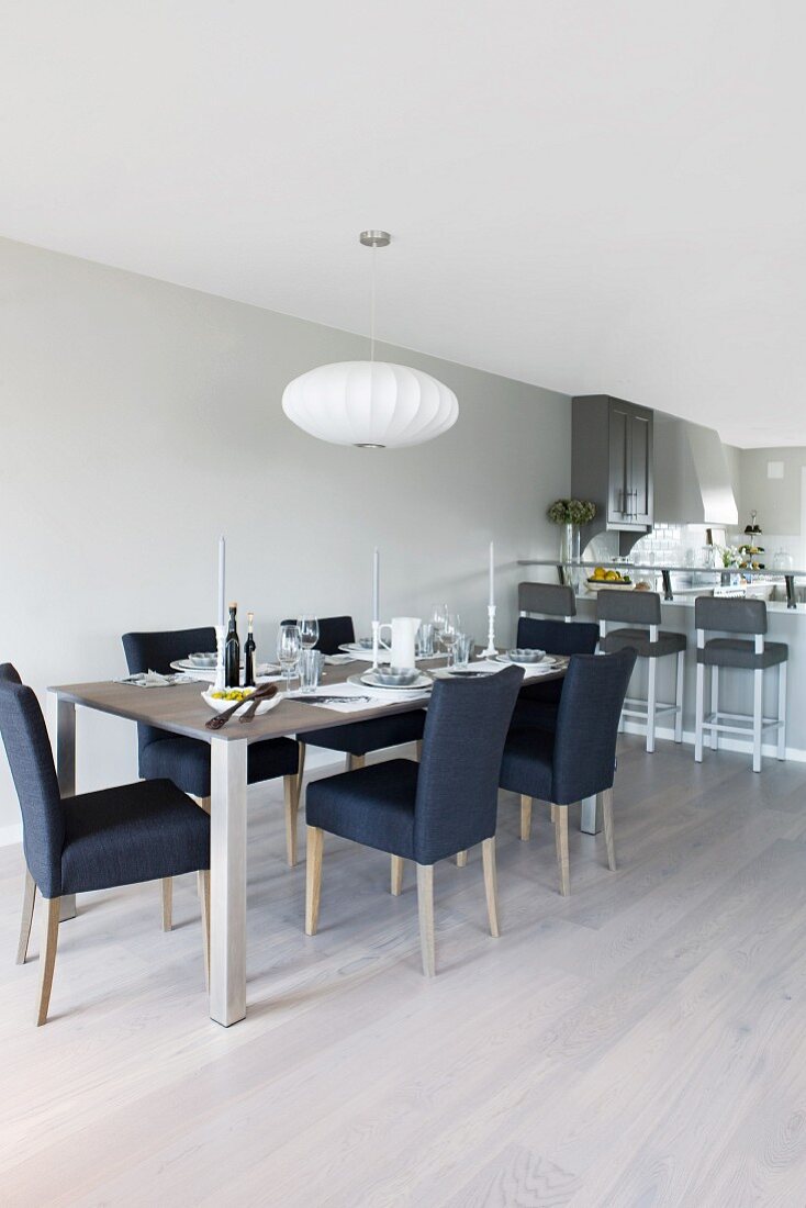 Essplatz in gedeckten Farbtönen und skandinavisch, klarem Stil in offenem Wohnraum mit Küchenbar im Hintergrund
