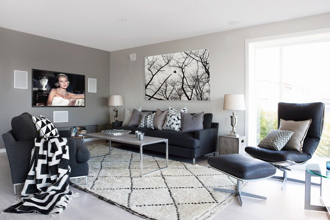 Charcoal seating area with graphic patterns on cushions and blanket; flatscreen TV showing film and poster of trees on wall