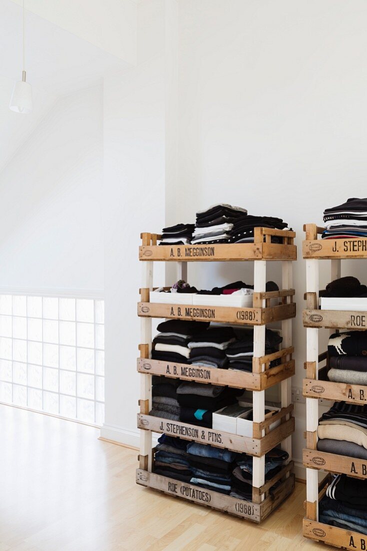 Stacked fruit crates used as creative shelves for clothing in loft-style bedroom