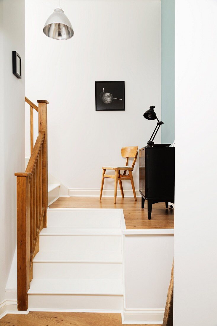 Treppenabsatz mit schwarzer Vintage Kommode und Foto an der Wand
