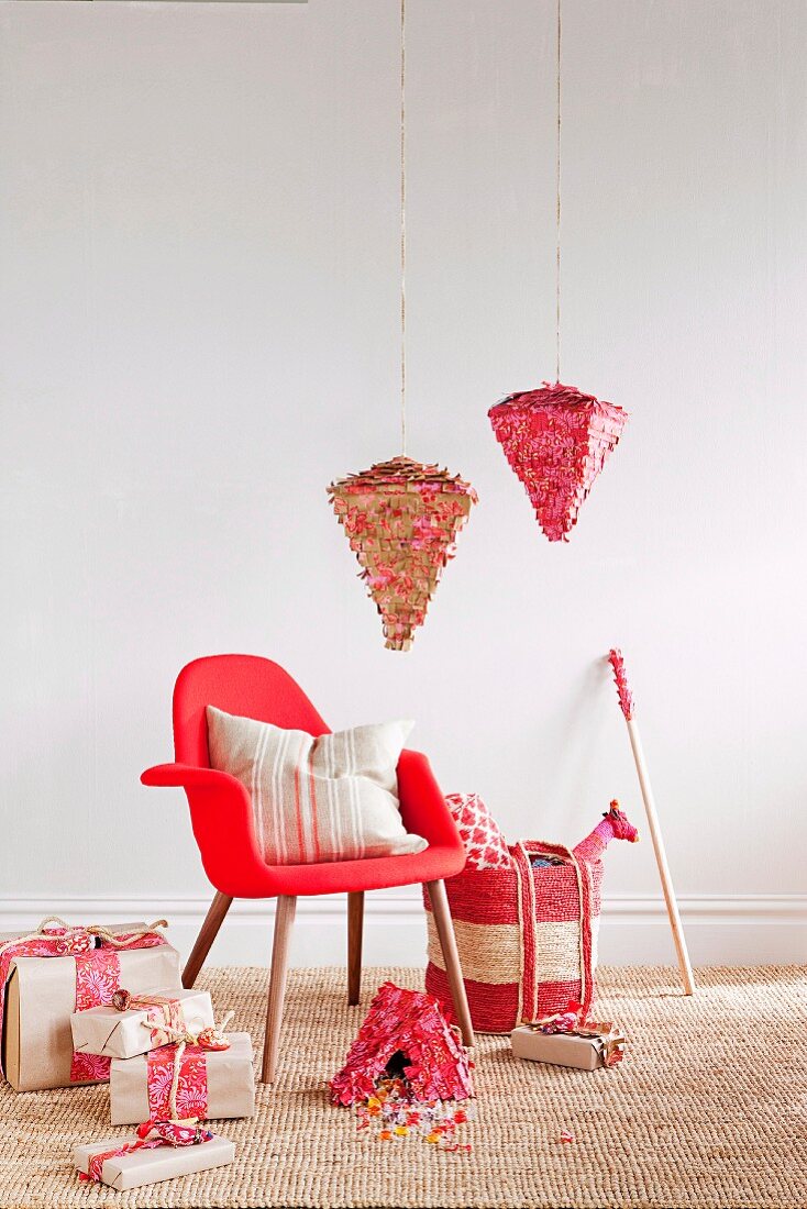 Pinatas hung over a red armchair and wrapped presents next to sweets on sisal carpets
