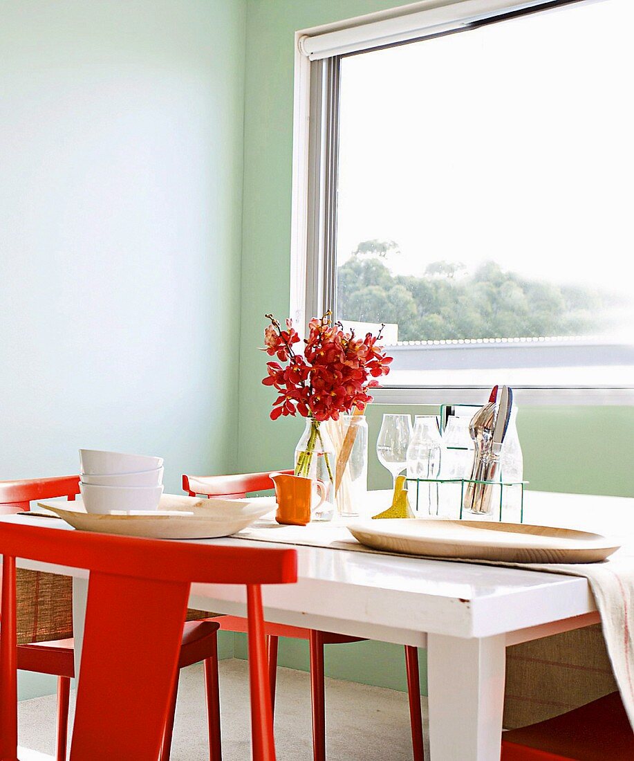 Red chairs and white dining table below window