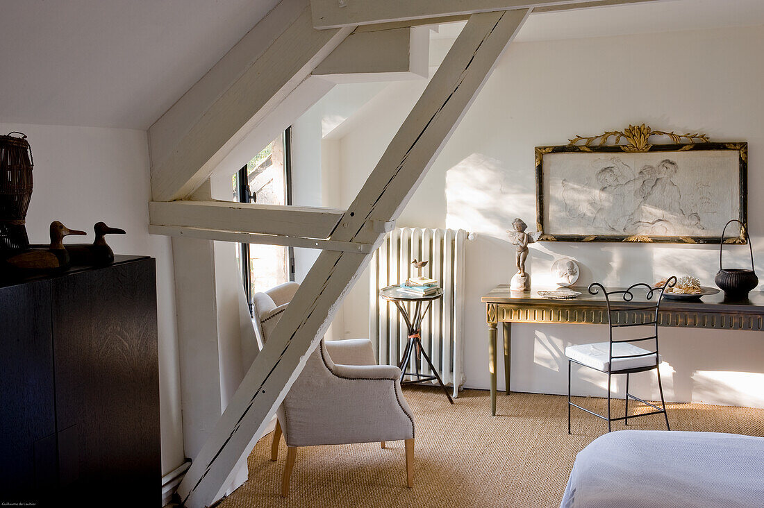 Attic room with white-painted wooden beams, art and vintage furniture