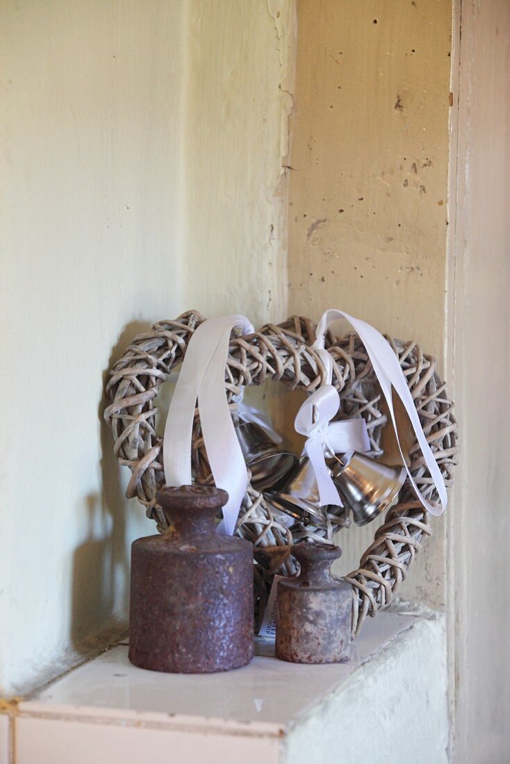 Two old metal weights in front of woven wicker love-heart