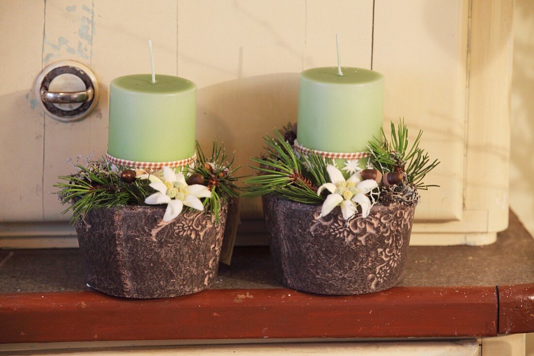 Green candles, branches and edelweiss in small pots