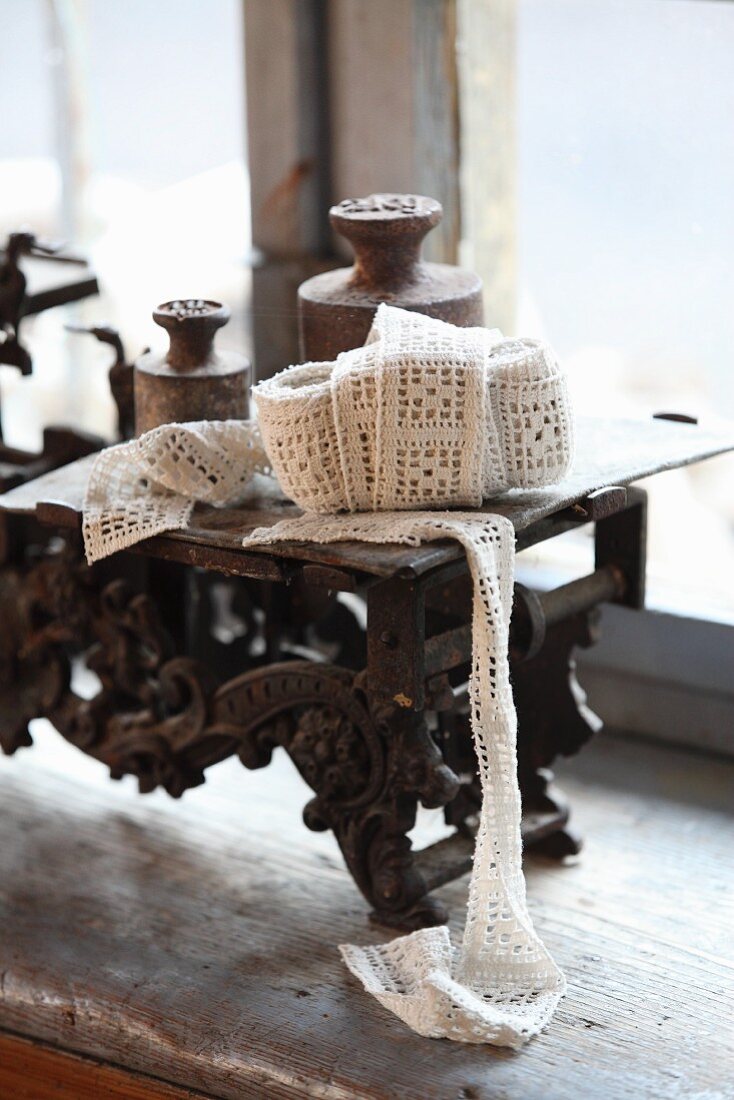 Ball of fabric ribbon and old weights on set of old scales on windowsill
