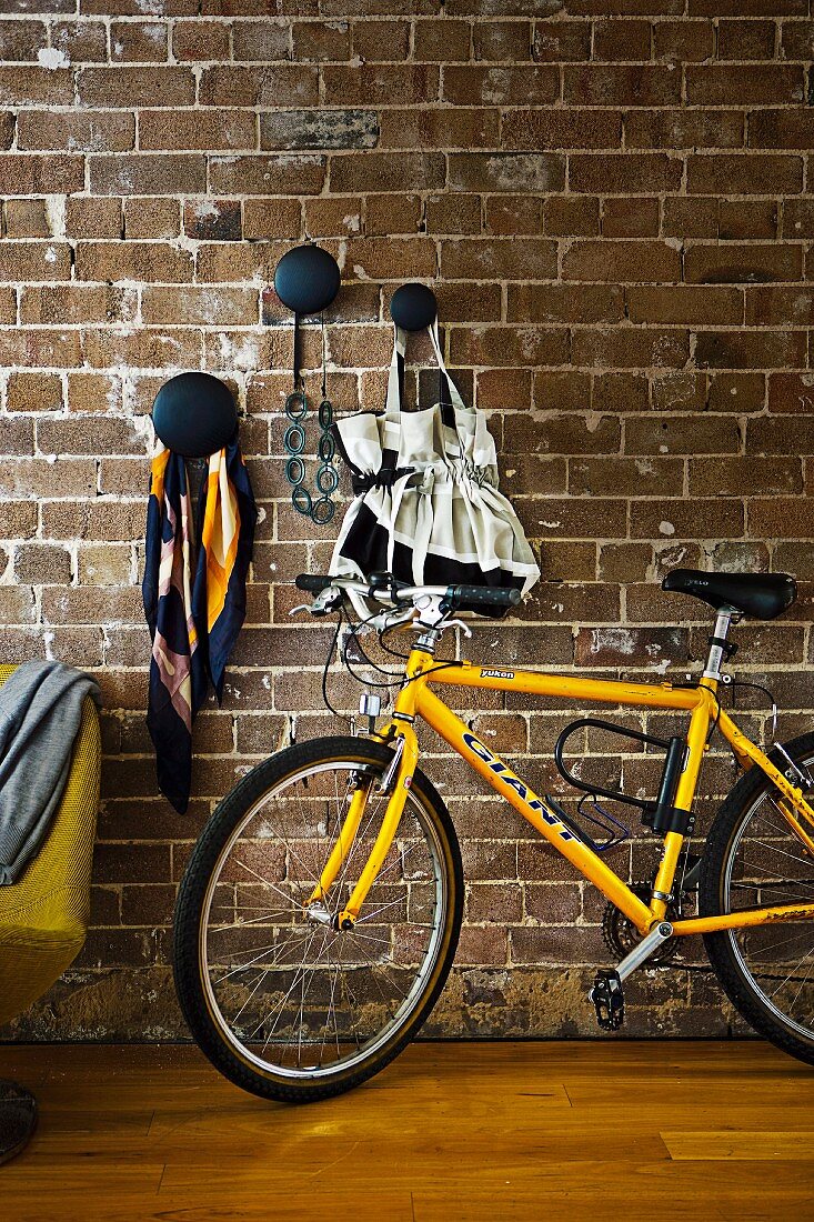 Fahrrad angelehnt vor Ziegelwand mit dekorativen schwarzen Wandhaken zur Aufbewahrung für Taschen & Utensilien