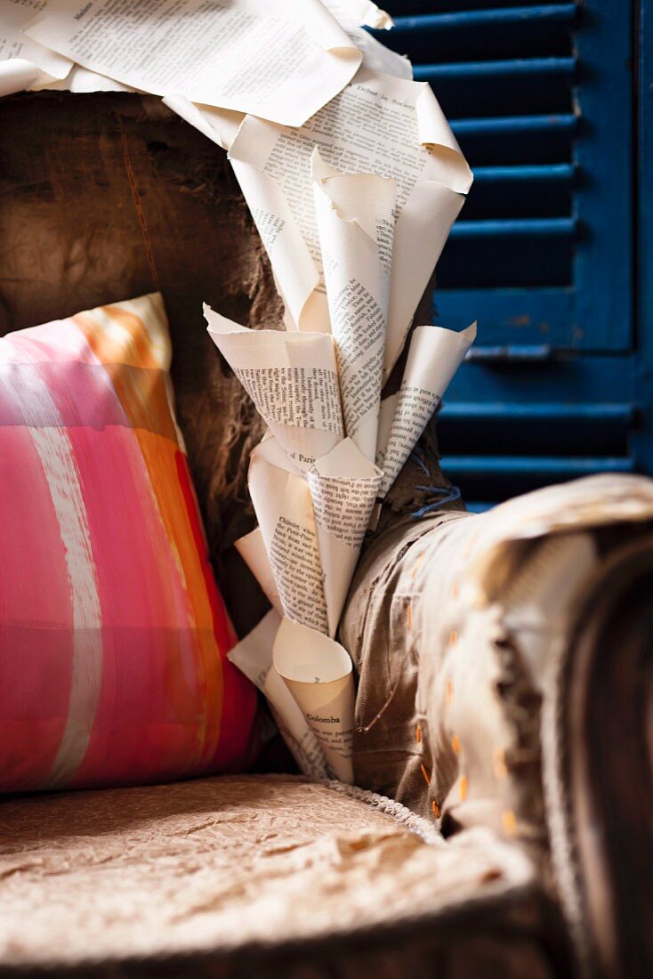 Ausschnitt eines Sessels mit tütenartig gerollten Bücherseiten dekoriert