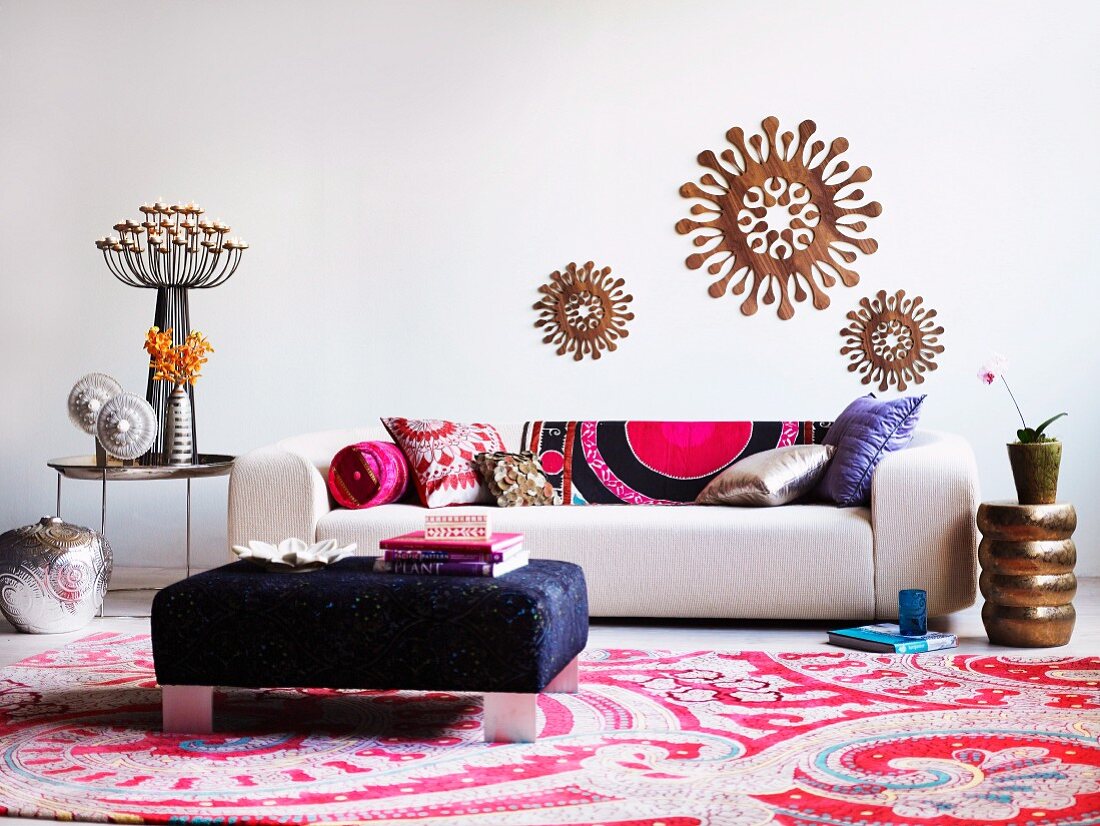 White sofa with patterned cushions, blue ottoman and Oriental rug decorated with various home accessories
