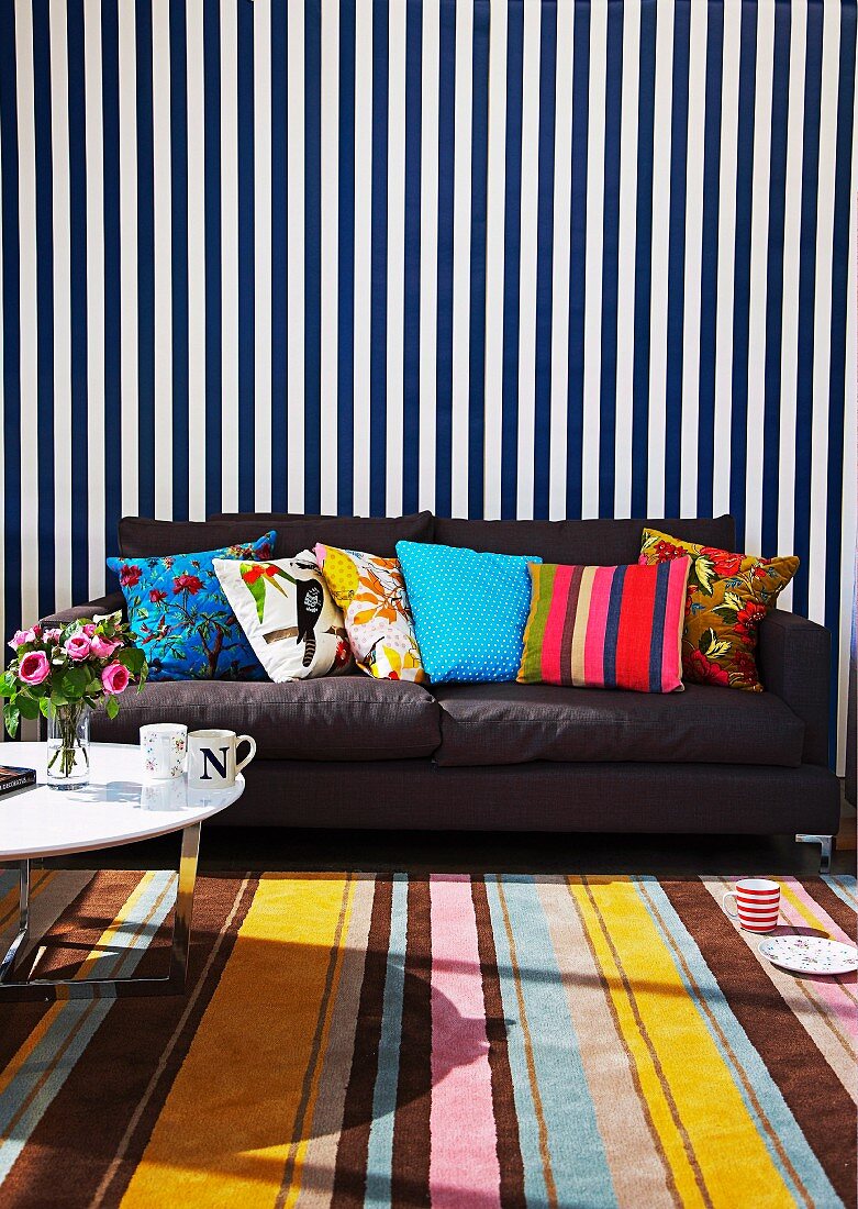 Mustermix - Streifenmuster auf Teppich und Wandbehang davor dunkelgraues Sofa mit bunte Dekokissen