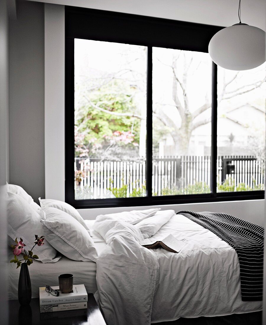 Single bed next to large window in grey and white bedroom