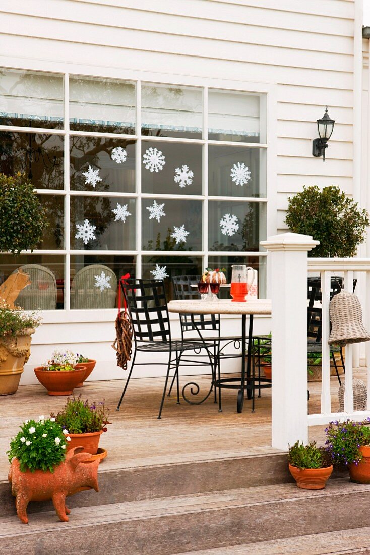 Terrasse vor weihnachtlich dekoriertem Fenster eines weissen Holzhauses