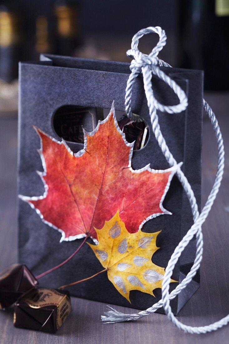 Kleine Geschenktüte verziert mit bemalten Herbstblättern