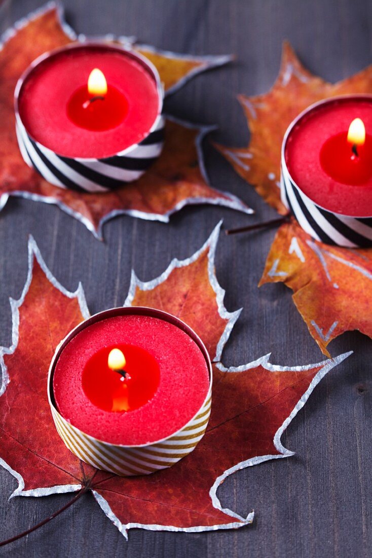 Painted autumn leaves used as coasters for tealights covered in washi tape