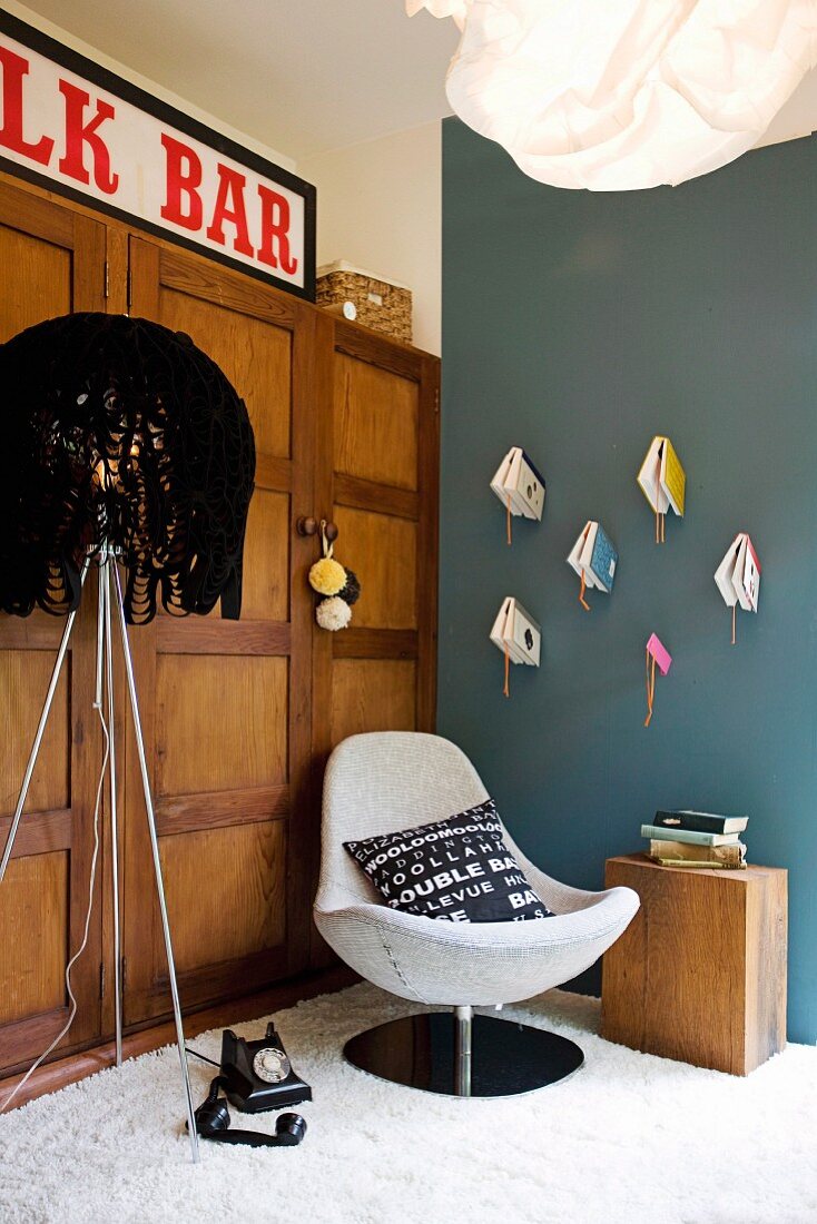 Gemütliche Sitzecke im Vintagestil mit Stehlampe, Schalensessel & griffbereiten Bücher an selbstgemachten Wandhaltern