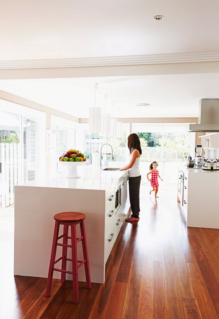 Open kitchen with white kitchen unit and retro bar stool, girl and woman in the background