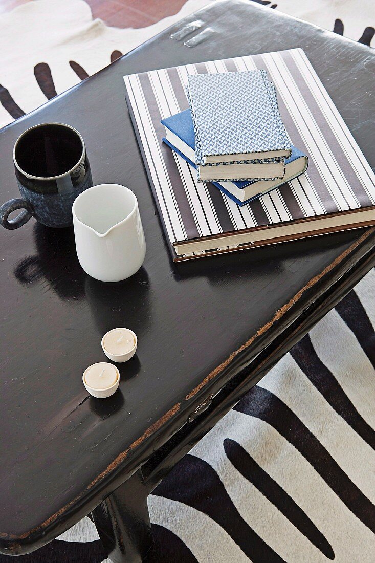 Books with DIY envelopes, mugs and tea lights on a coffee table