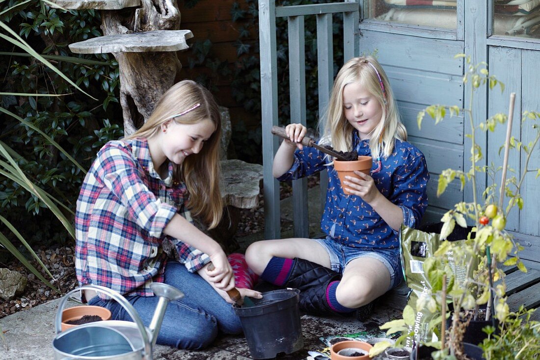 Zwei Mädchen bepflanzen Blumentöpfe